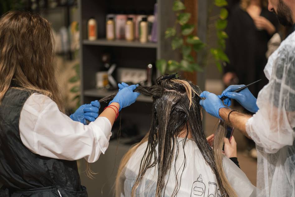 Founder holding up strands of highlighted hair in natural light